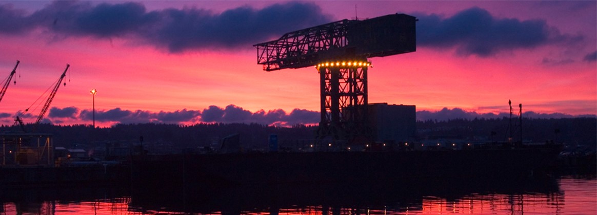 The historical hammerhead crane at Puget Sound Naval Shipyard & Intermediate Maintenance Facility in Bremerton, Washington, is silhouetted at sunrise. The PSNS & IMF hammerhead crane was built in 1933, and stands 250 feet (76 m) tall and 80 feet (24 m). In its heyday it could lift 250 tons.